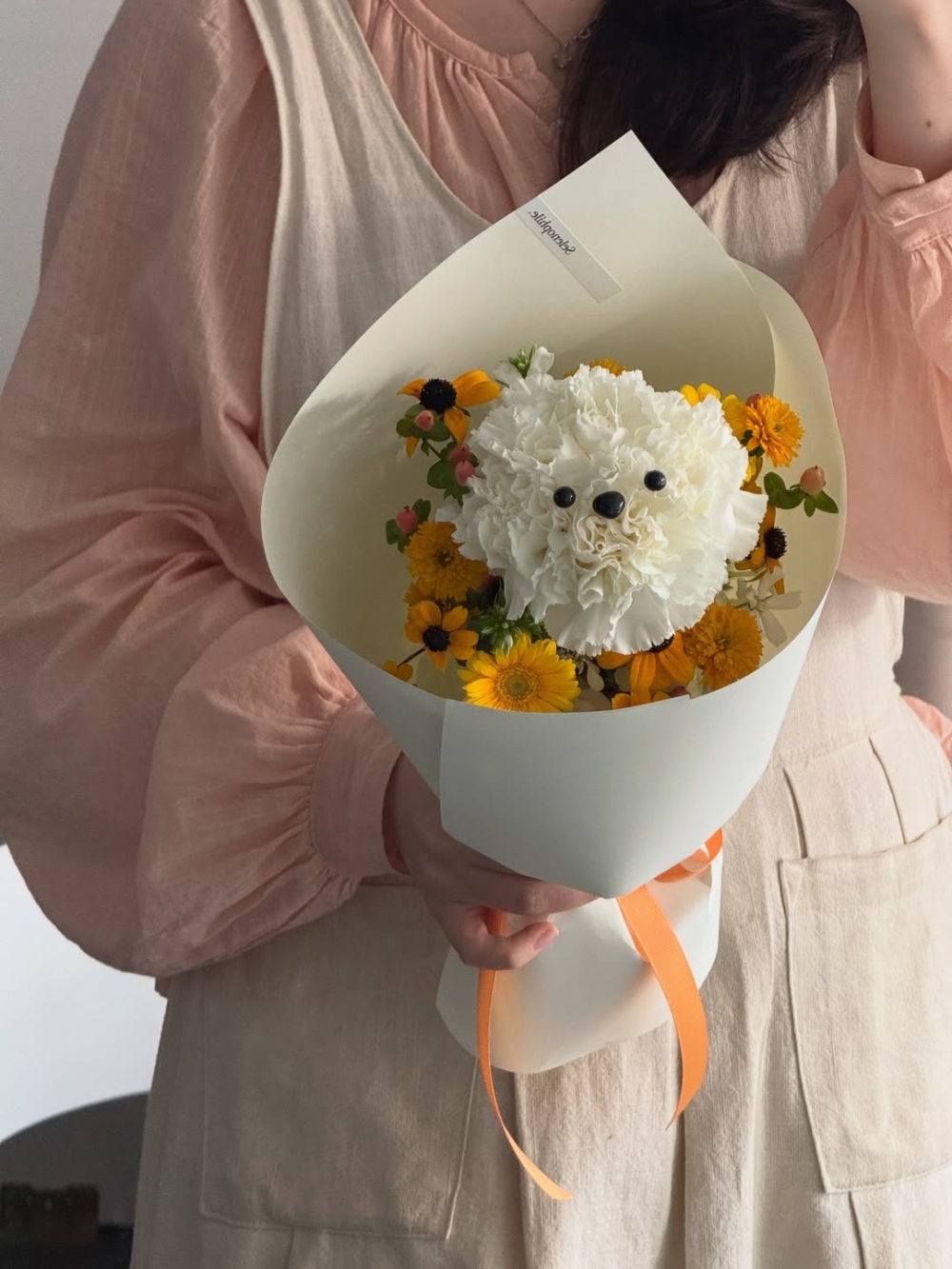 圓潤蓬鬆的乒乓菊，加上眼睛與耳朵裝飾，巧妙地勾勒出小狗的模樣，讓整個花束瞬間化身成栩栩如生的「萌寵」。