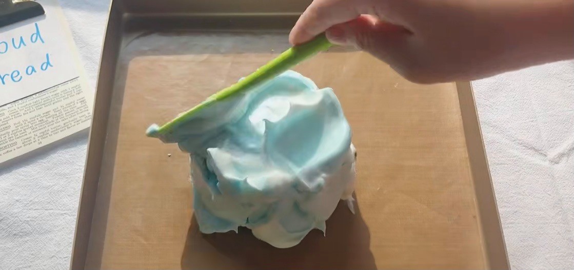 雲朵蛋糕-把打好的蛋白倒在鋪好牛油紙的烤盤上，把它盡量抹成球體狀或光滑的橢圓形狀。（想要有幾種顏色的話，就要分幾次打蛋白，然後在這一步把不同顏色的蛋白糊堆砌在一起！）