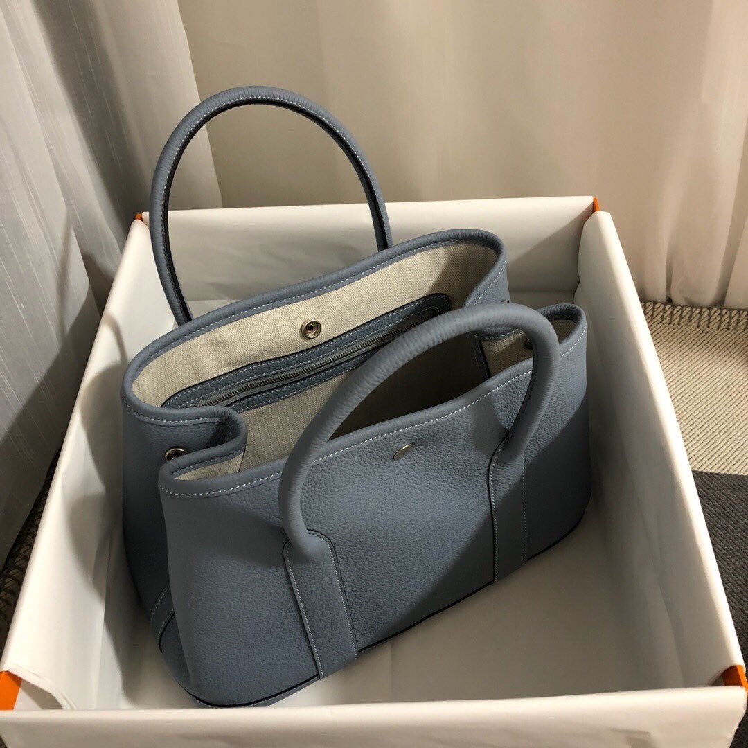 在Hermès Garden Party Bag手袋的開口處及側面都設有金屬扣子,只要把扣子扣上,手袋就會收窄了一點