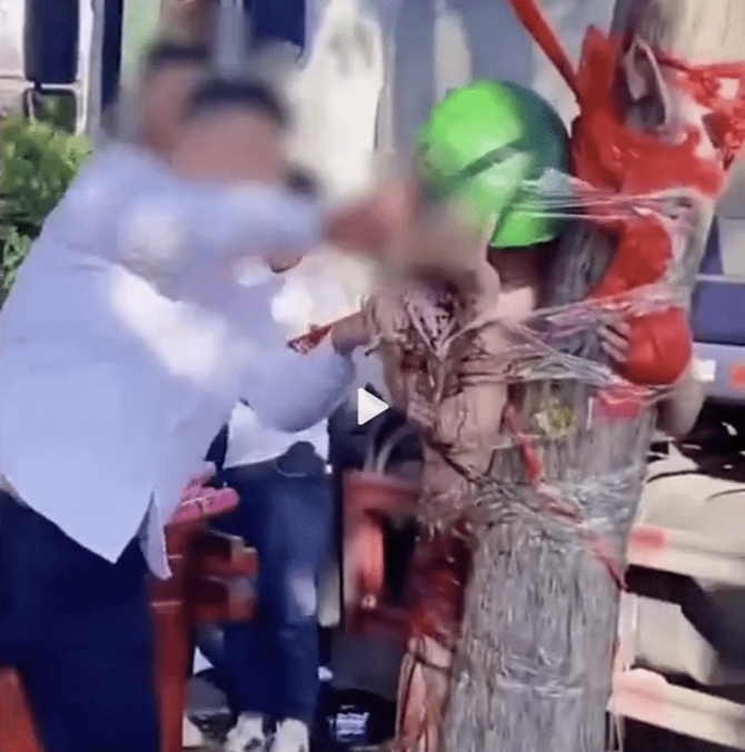 新郎被親友用膠紙綁在樹幹，並被人戴上一頂綠色的帽子和不斷扔雞蛋。