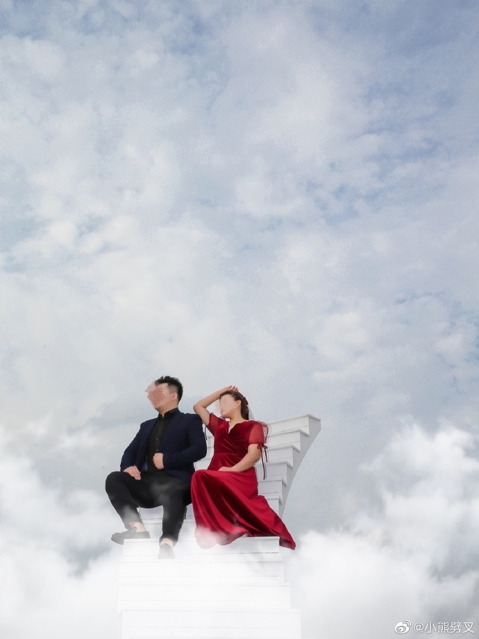 一對新人穿上黑、紅禮服在藍天白雲的佈景裡大擺 POSE