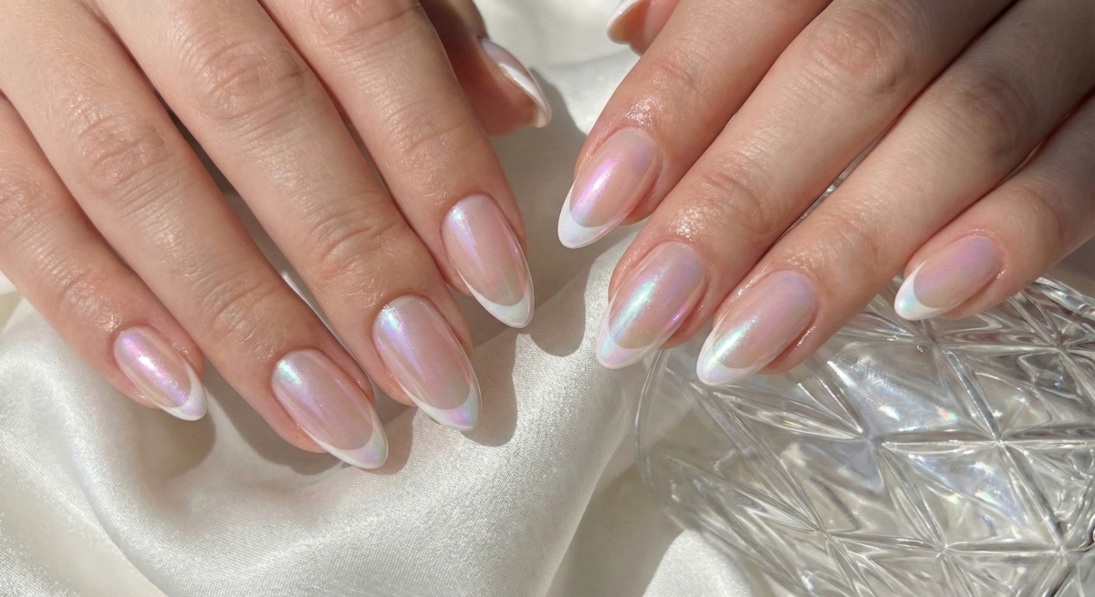 在保留法式線條的基礎上，於甲面掃上一層細膩的極光粉。這種設計保留了裸色底色的剔透感，同時讓指尖隨著光線折射產生神祕誘人的幻彩光澤。