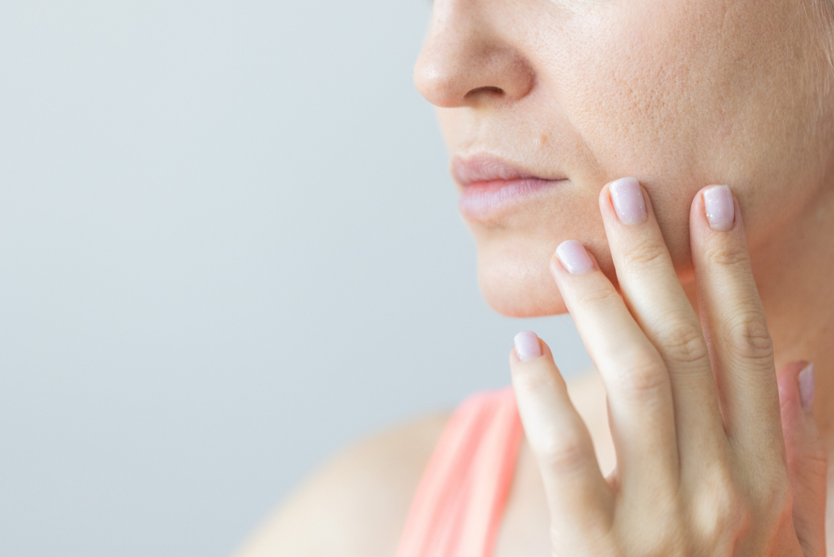 特寫鏡頭顯示女性輕觸鼻翼兩側至嘴角的法令紋位置，檢視面部肌膚紋理與深淺，示意面相學中對『壽帶』、威嚴性及中晚年運勢的分析與關注。