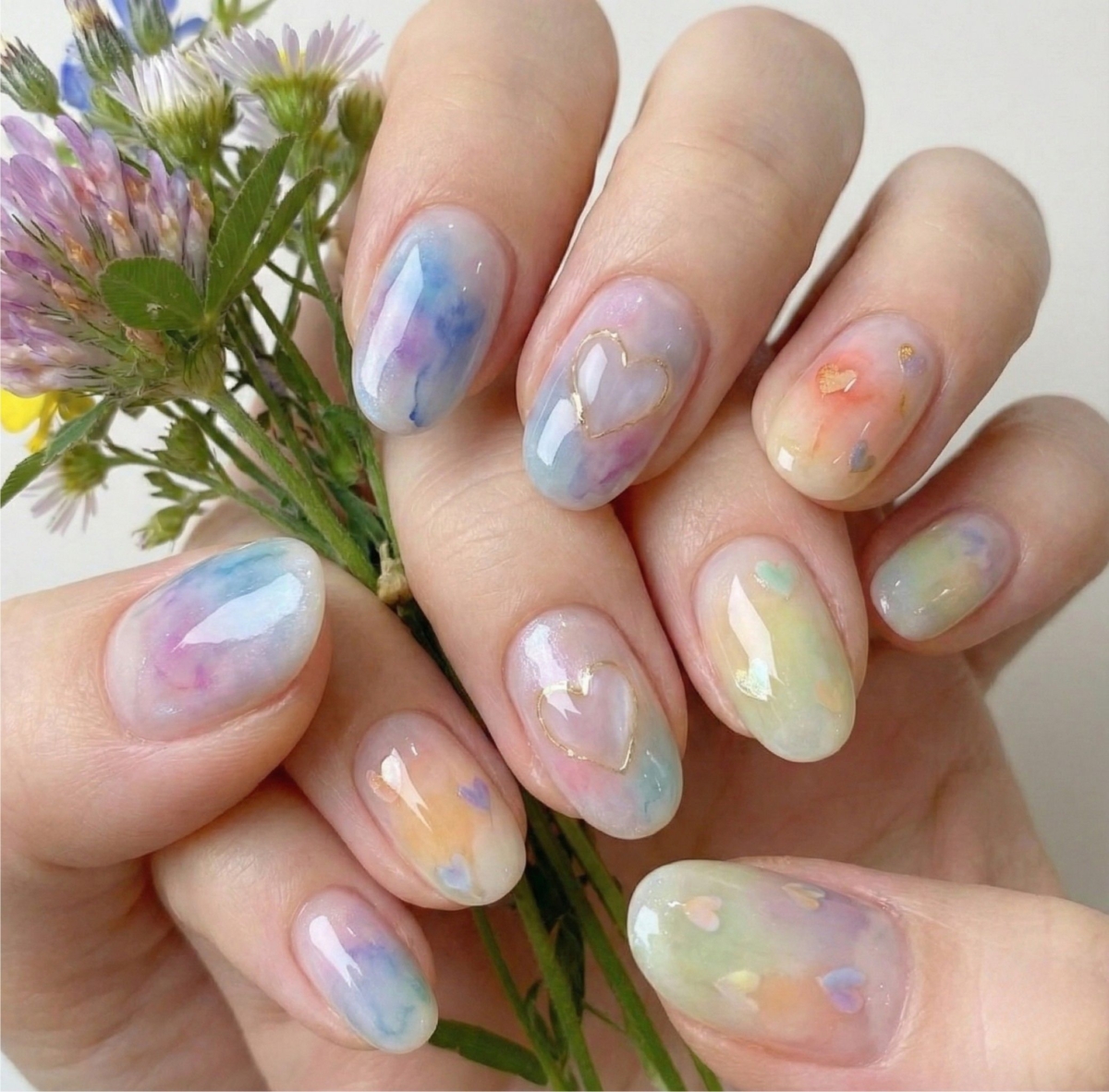 圖中這款水彩美甲運用柔和暈染與輕盈漸層效果，搭配亮粉或珠光設計，打造如水彩畫般的藝術感指尖。