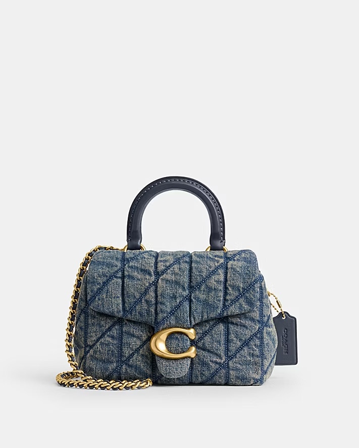 這款 Coach Tabby 絎縫丹寧頂部提把手袋，將 1970 年代的經典款式以現代手法重新演繹，展現出復古與都會感的完美結合。