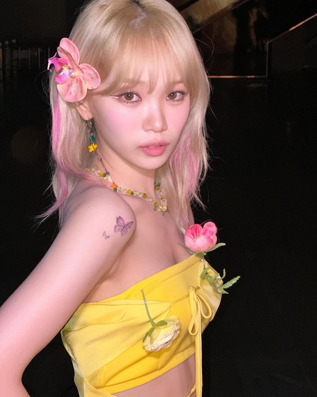 在極具光澤的白金髮基底上，設計師運用「面部框架染（Money Piece）」的技巧，將最靠近臉頰的兩側髮束染成鮮豔的粉紅色。