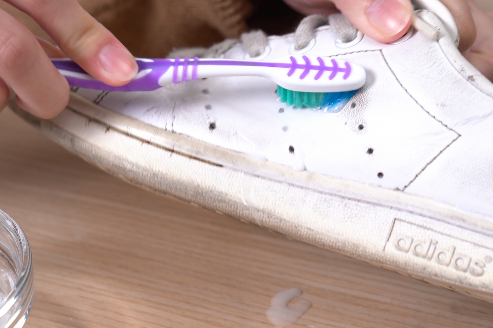 倒出適量的梳打粉，加入少少水將梳打粉稀釋，用牙刷沾一些梳打粉，輕力擦走表面的污漬，擦完後用濕毛巾抹乾淨，再將白鞋放在陰涼的地方自然風乾。