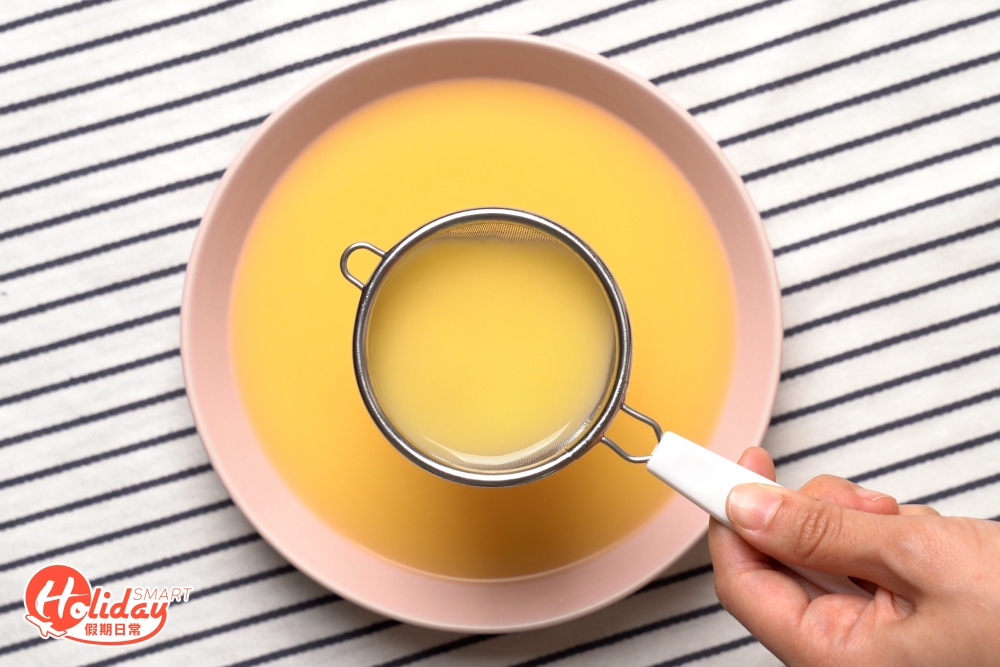 用隔篩把蛋液注入碟內，再用小匙勺去掉小氣泡，可令蒸出來的蛋表面更平滑。