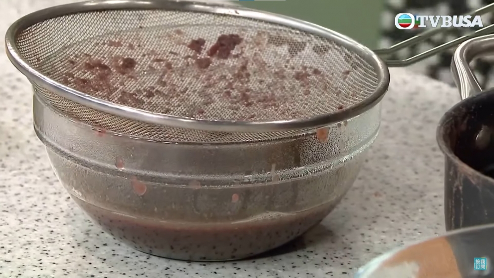 用器具如湯勺按壓紅豆成紅豆沙。