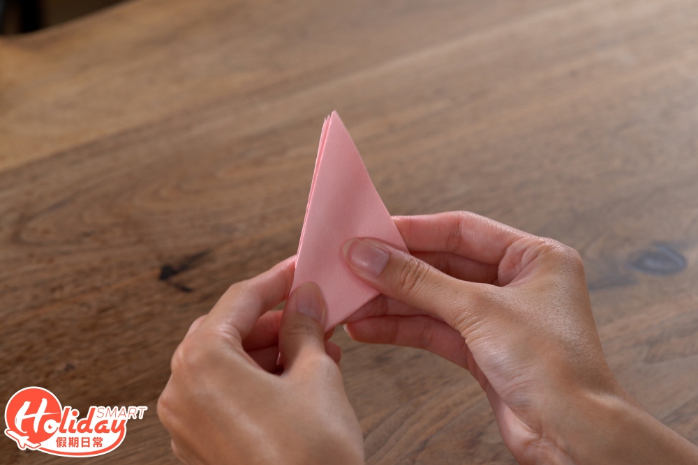 1.將正方形的顏色紙打斜對摺3次,摺成一個三角形。