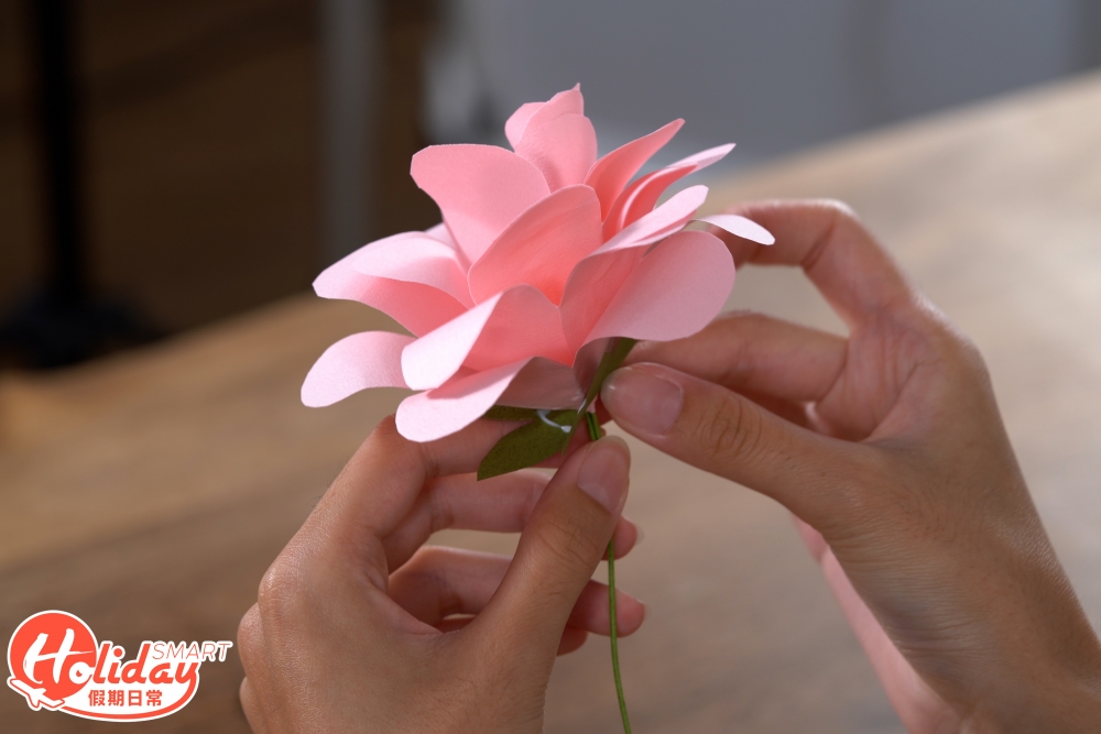 9.之後摺花托部分,先將正方形的顏色紙打斜對摺3次,再剪成樹葉的形狀,剪掉尖角,用膠水將花托與花瓣黏合。