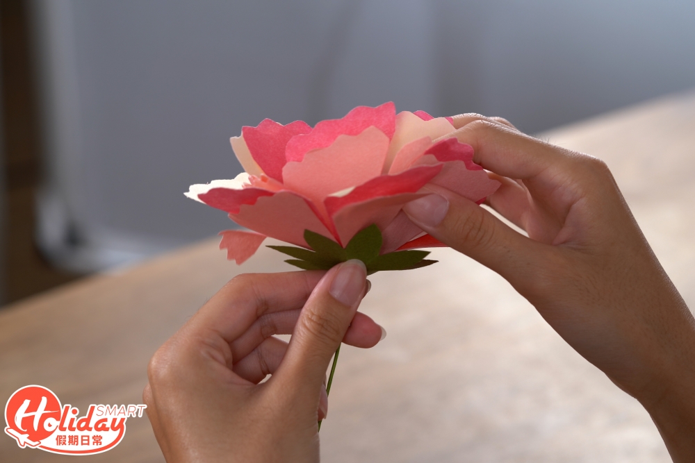 7.之後摺花托部分,先將正方形的顏色紙打斜對摺3次,再剪成樹葉的形狀,剪掉尖角,用膠水將花托與花瓣黏合。