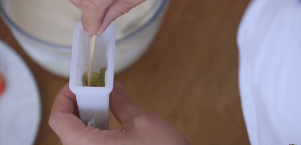 水果片貼在模具內邊上，並用木棍固定位置。