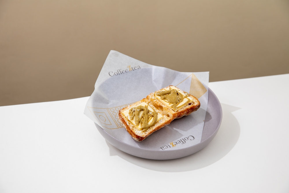 鮮油占多命名為「開心好多」,有別於茶餐廳的白麵包,這裡改用意式拖鞋包,配以大大片的法國牛油及意大利產的開心果醬。