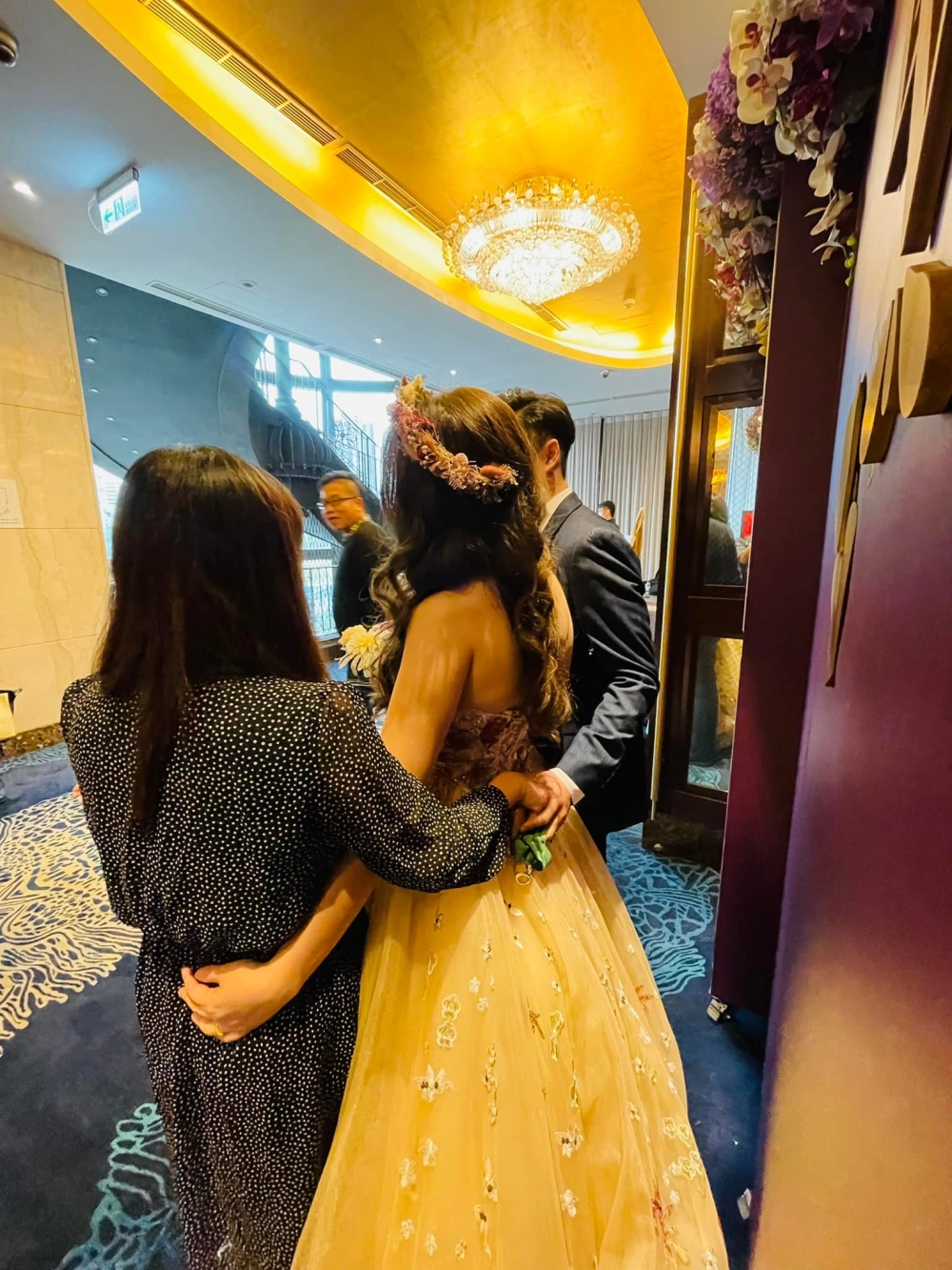 相中新娘新郎正一同接待賓客,新娘旁邊仲有一位著黑色波點裙嘅女賓客。