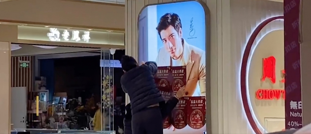 有內地傳媒影到商場有工作人員以傳單遮住王力宏嘅廣告牌。