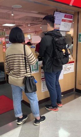 片中一男一女正喺壽司郎門口等候入座,女士表現十分不耐煩:「要等幾耐呀?快啲啦!」
