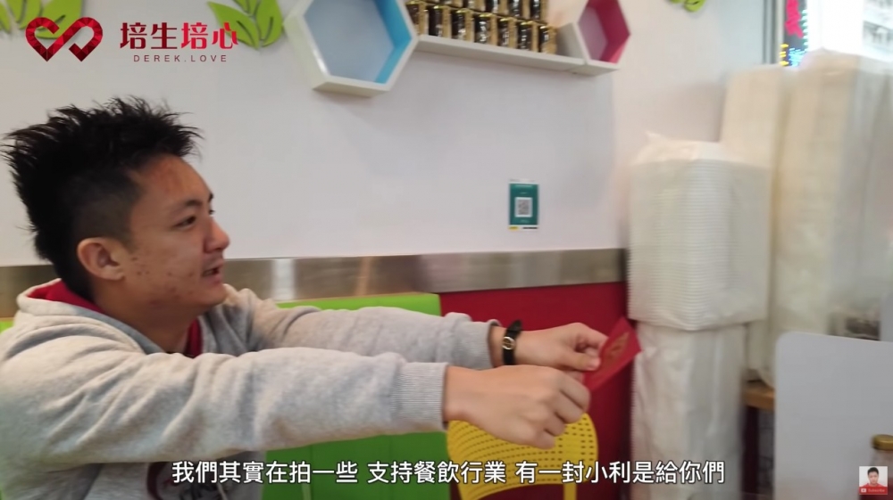 片中鍾培生將一大疊$500紙幣放入利是封,派畀茶餐廳老闆