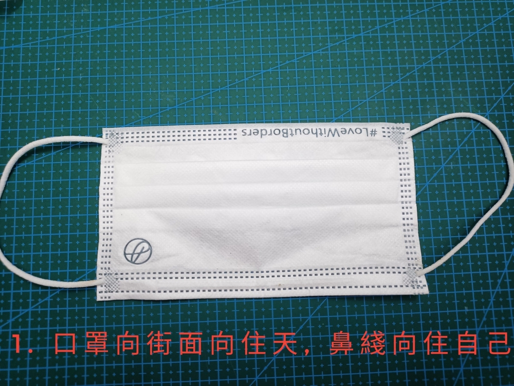 口罩平放枱面，外面向上放，鼻線近自己。 