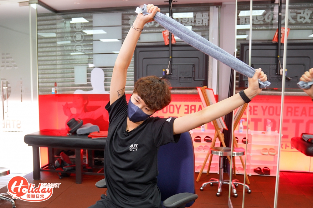 首先要準備一條毛巾作工具，將毛巾捲成條狀，雙手握著毛巾兩邊，右手施力，將身體慢慢傾斜向右邊，直至左邊腰部有拉扯的感覺。