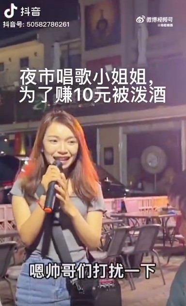 片中可見女歌手身穿灰色上衣、牛仔裙，面容清秀，佢行近其中一圍顧客，並主動問客人想唔想點歌