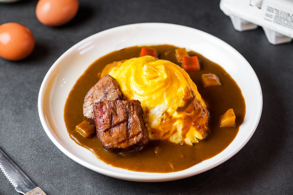 門口呈屋子形狀的尖沙咀蛋包飯專門店「米炊食堂」,裝修走日系簡約風,店舖之所以叫「米炊」,是源於創辦人鍾情於日本米飯,故開設以米飯為主題的和風家庭料理食堂。