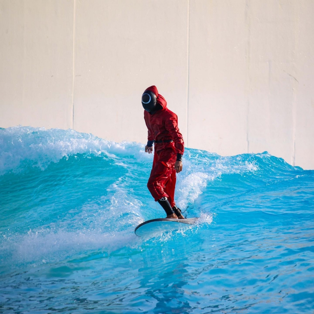 有人直接穿著韓劇《魷魚遊戲》中工作人員嘅紅色制服去衝浪!