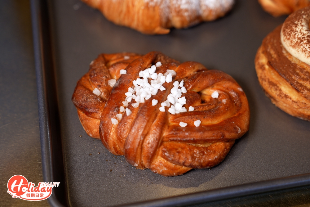 這款新酸種肉桂卷與普通的肉桂卷味道不同，採用錫蘭肉桂製作，之後塗上黑糖烘焙，最後特別加上珠糖點綴，包身比較平薄，不過味道卻比較甜。