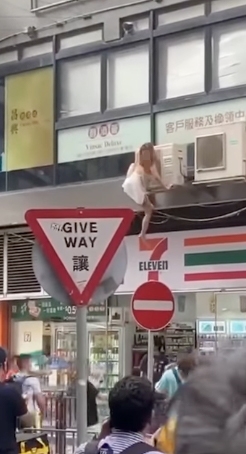 女子只係用雙手握住個冷氣機就想跳落地面！