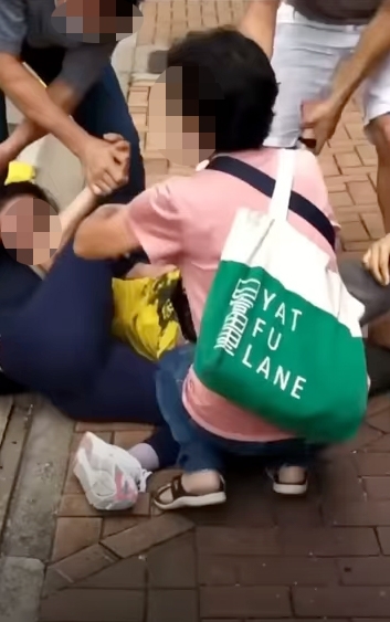 身穿粉色衫嘅女士主動加入幫手解開「腳結」