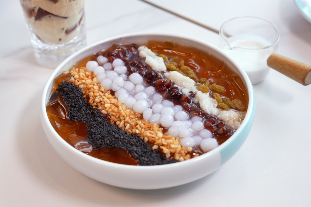 軟滑冰粉上鋪上黑芝麻、花生脆、提子乾、紅豆和脆珍珠等配料。冰粉烏龍茶味香濃，淋上清甜椰奶，甜甜的清爽口感好解辣！