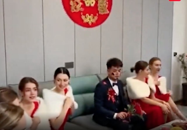 新郎坐喺梳化中間,兩邊分別坐咗幾位烏克蘭伴娘,新郎目不斜視,未有多望伴娘。