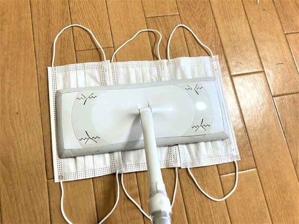 再將三個口罩平排地綁喺除塵拖把上面