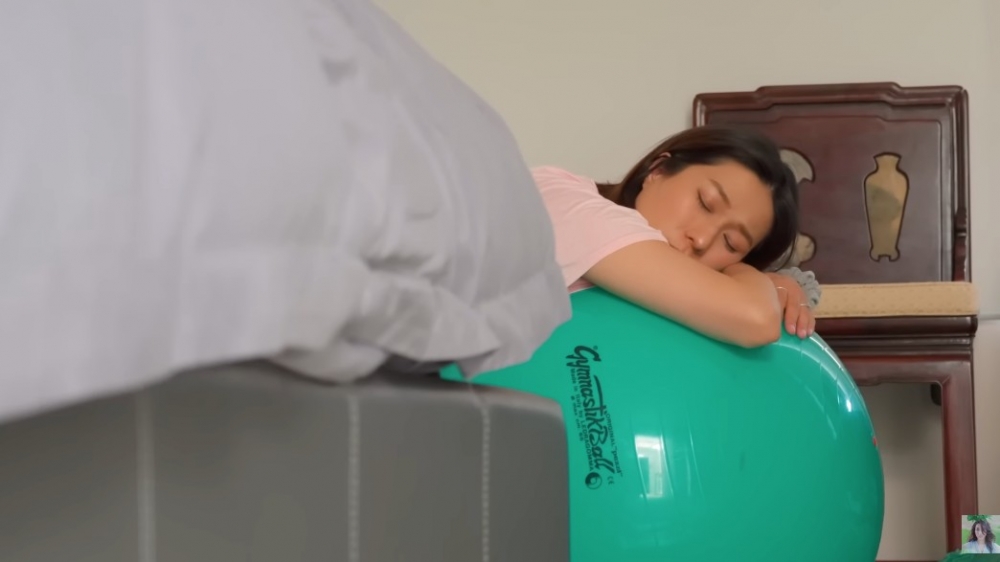 難掩緊張的她躺在健身球上