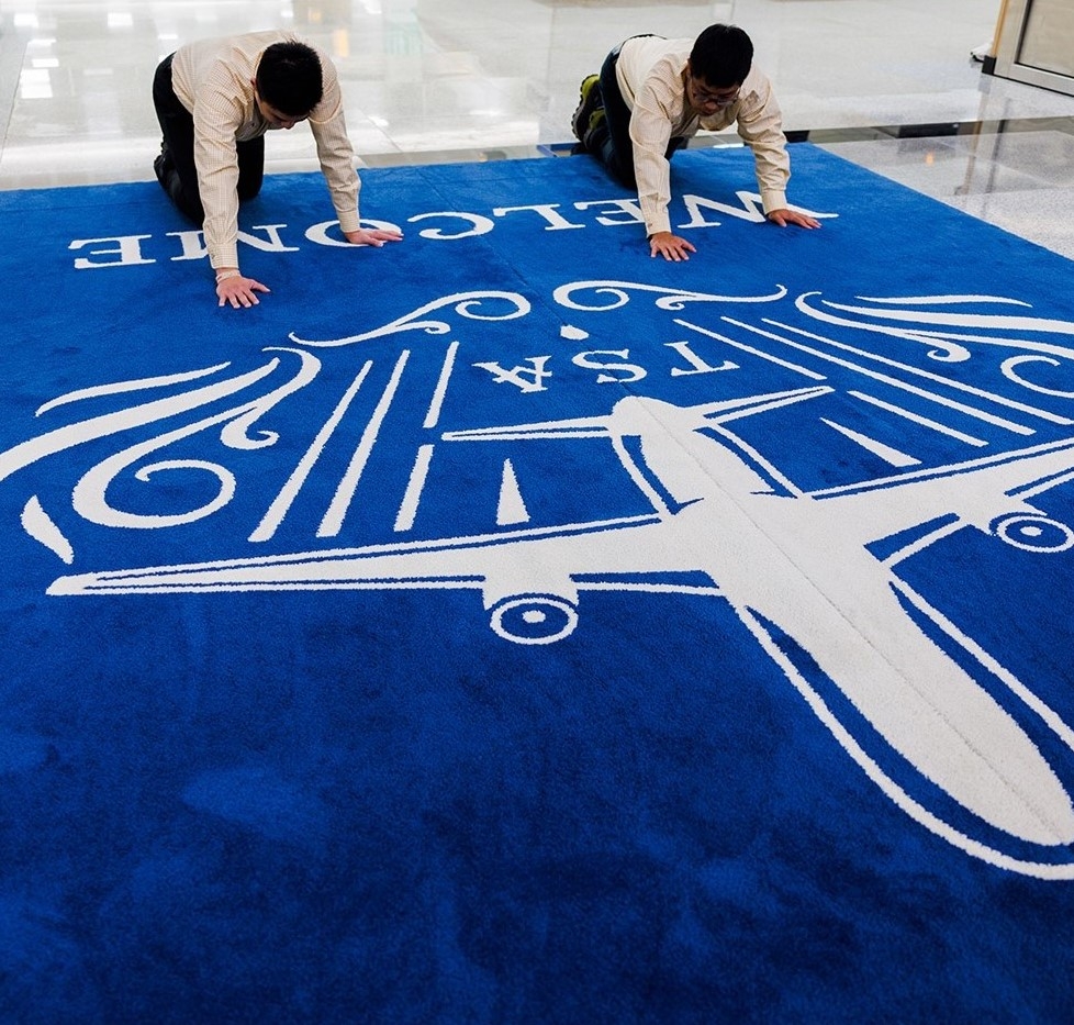 從1樓前往2樓的美食商場前，地上鋪設了兩塊寶藍色地毯，拼接在一起係代表松山機場的白色飛機標誌！