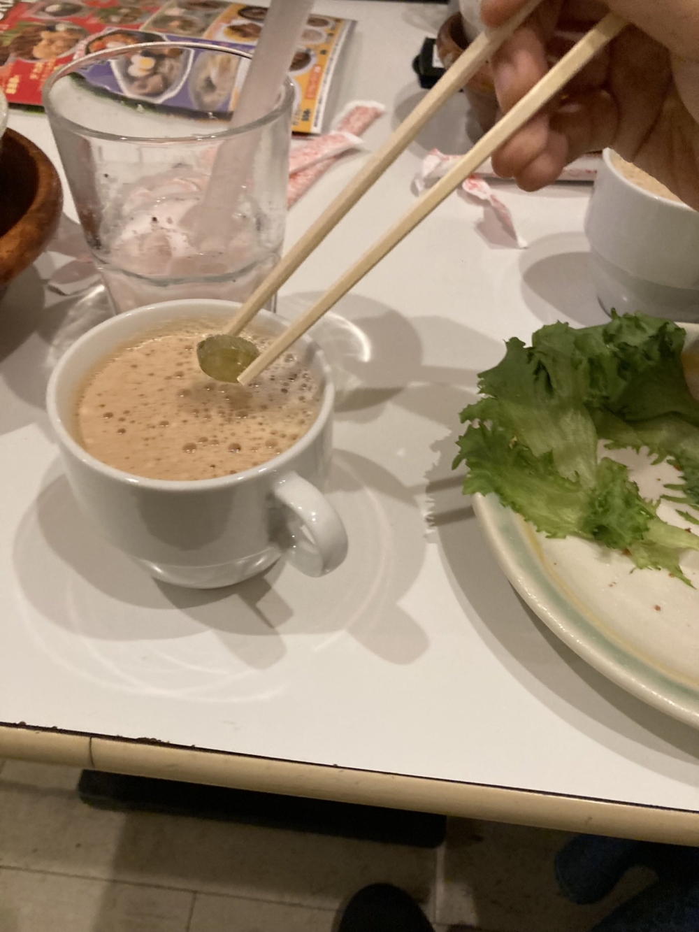 將一顆龍角散潤喉糖丟入小杯的熱奶茶