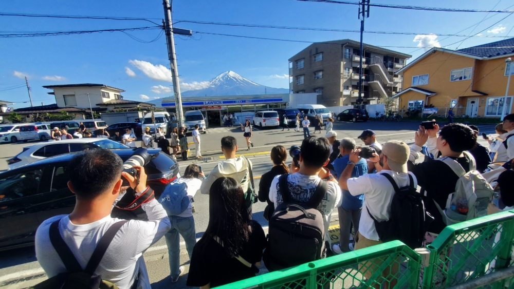 以富士山為背景的LAWSON河口湖站前店,因為一直聚集大批遊客打卡而出現各種擾民問題,政府於5月在該打卡熱點前立起一道巨大黑幕遮擋富士山景色,以阻止遊客拍照打卡!