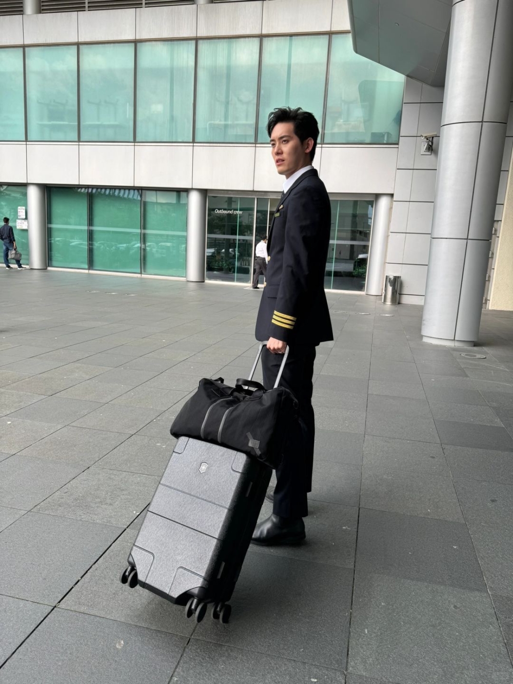 相中盛勁為身穿黑色機師制服，拉住行李喼，非常專業