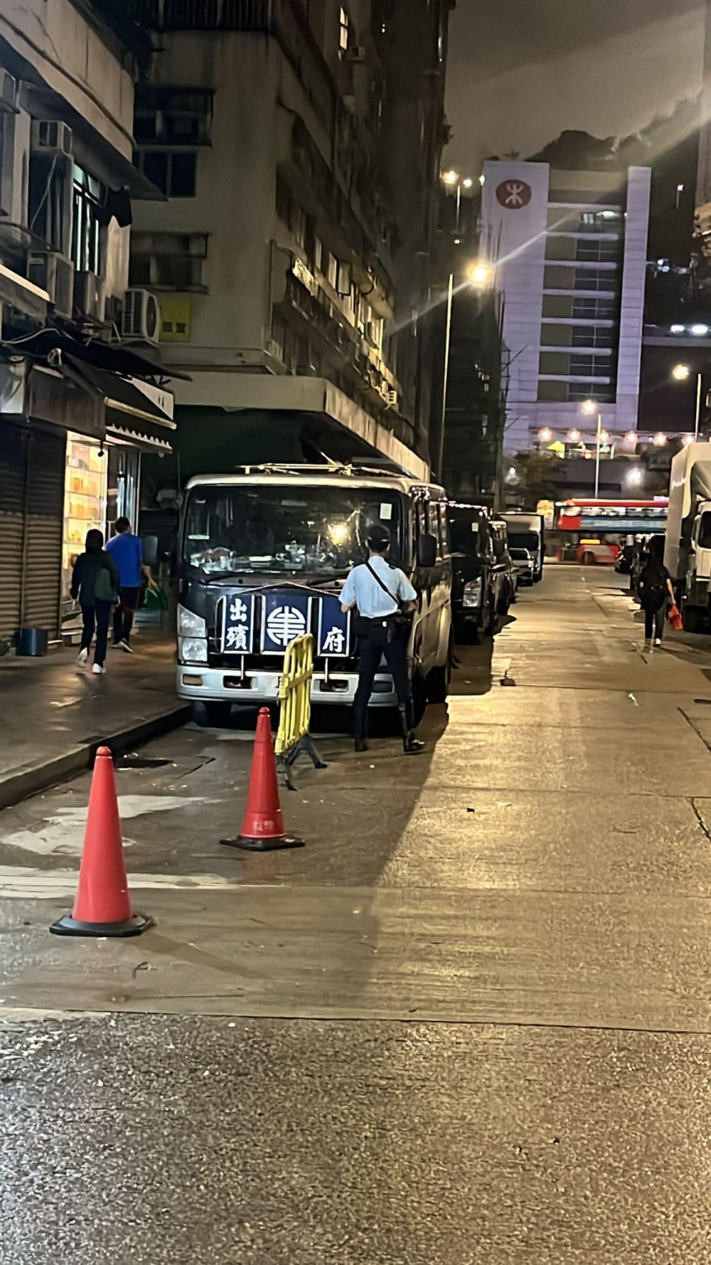 停泊在路邊的一架靈車前方站著1名警察，相信正在抄牌