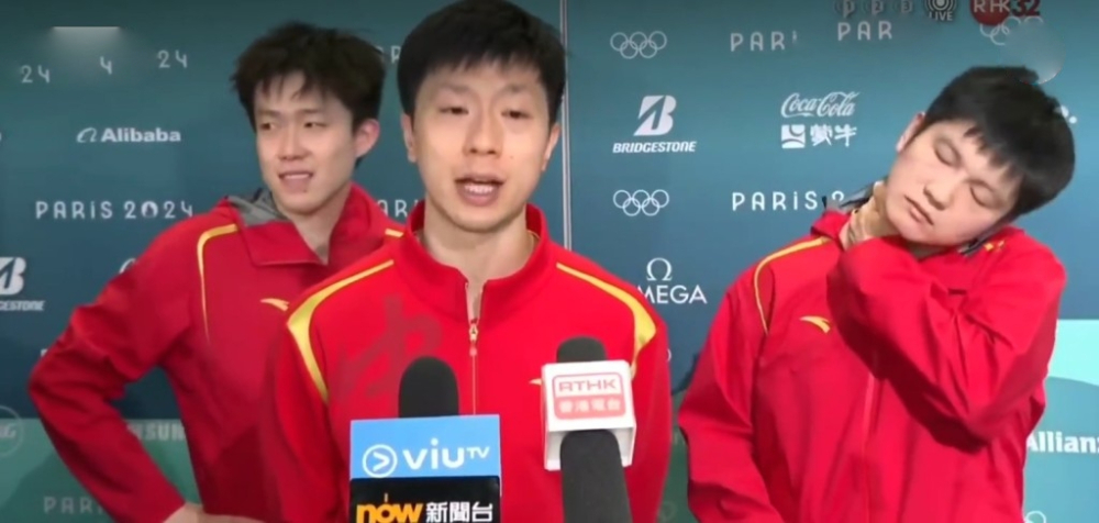 團中「老大哥」馬龍被推了出來發言。期間兩名隊友則站在其身後「食花生」