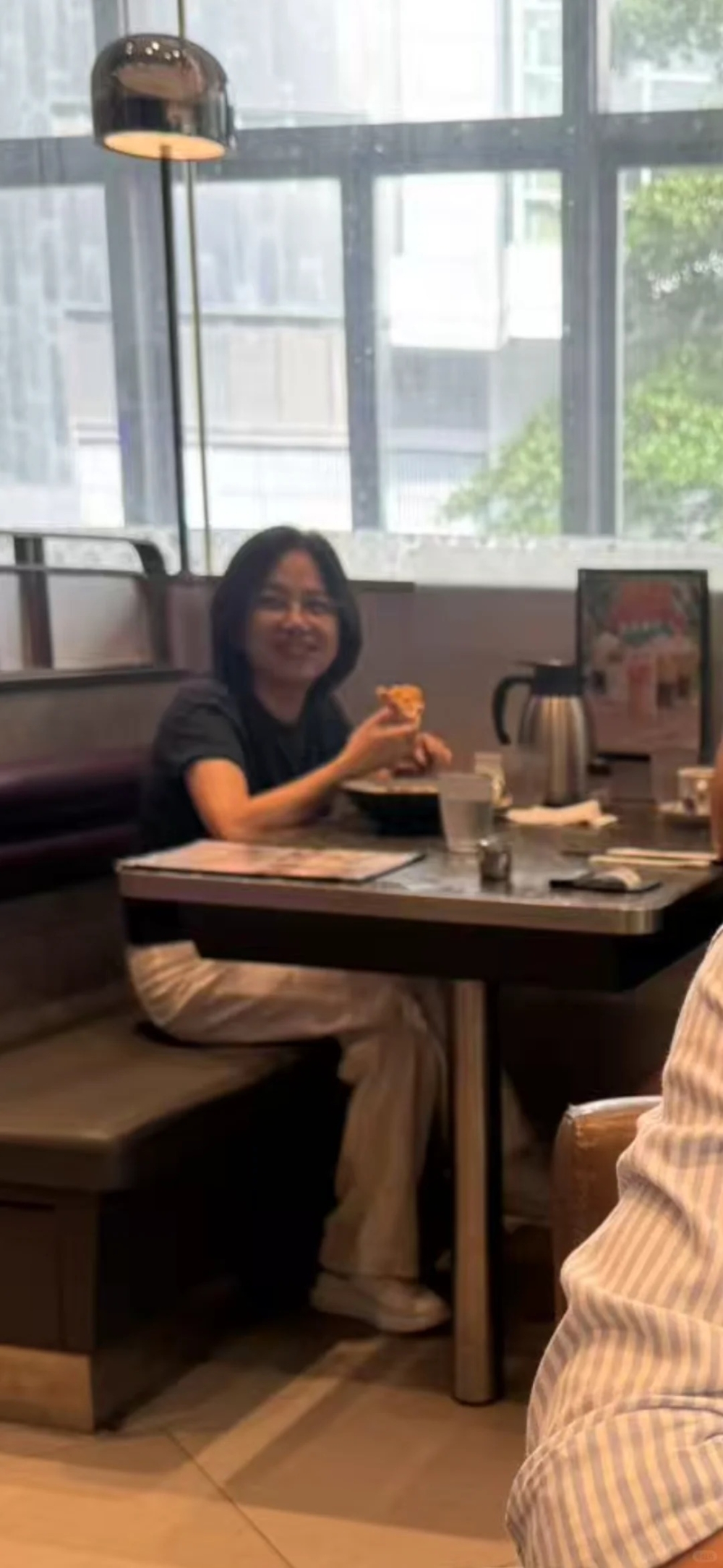 容佳文身穿黑色短袖Tee及白色長褲，以及白色休閒鞋，正在茶餐廳內醫肚，全程極從容！