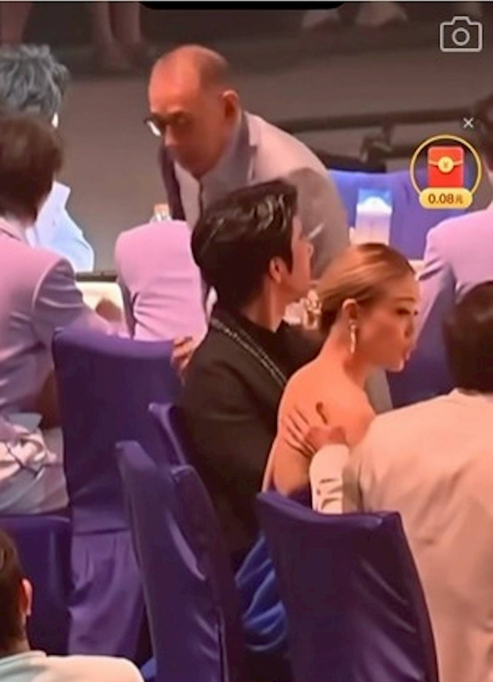 成龍原本搭在容祖兒椅背上的手竟滑到她的玉背上，並輕拍了兩下。