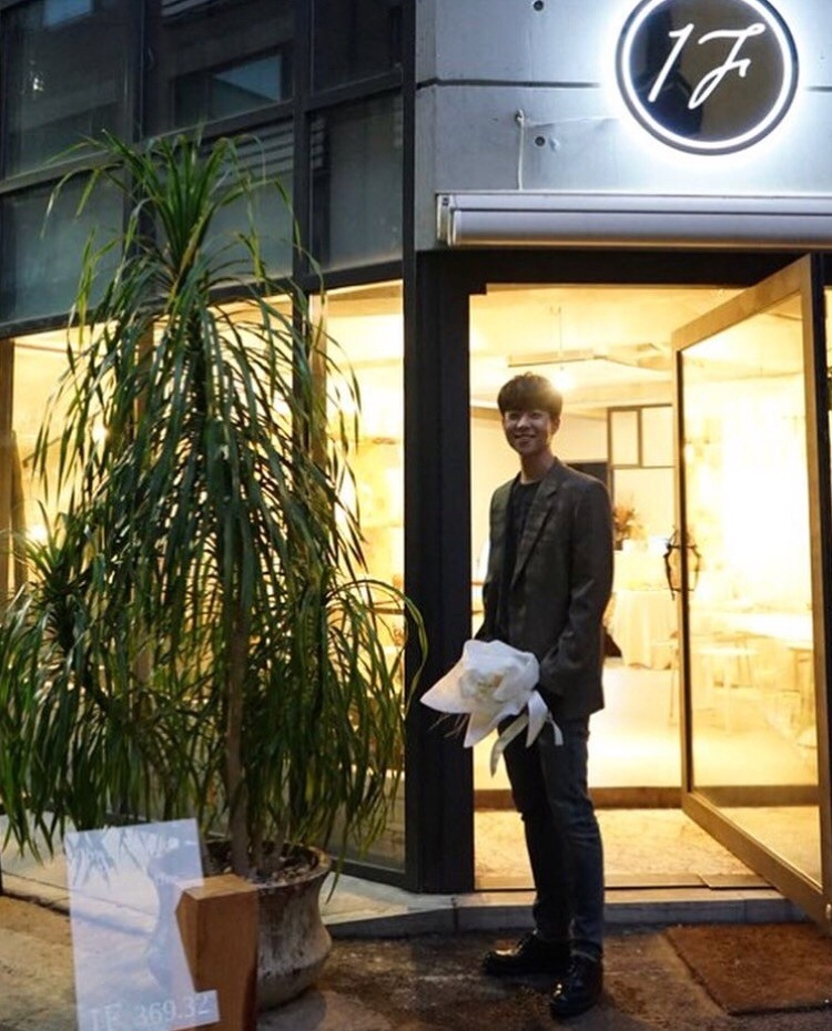 蔡鍾協拿著花在店門口迎接