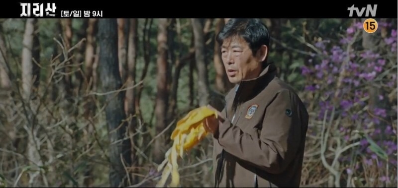 在出現李世旭遺體的畫面前，看到了曹大震（成東鎰 飾）手拿黃色絲帶上山的場景